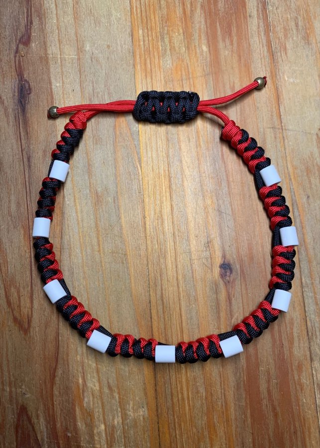 Collier coulissant à plat&nbsp;: tressage torsade noir et rouge, perles de céramique blanches, et le nœud coulissant noir qui le règle