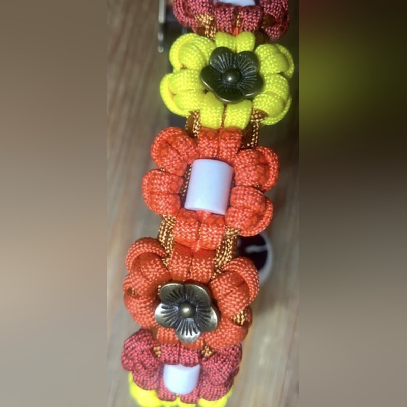 Collier Flowers en gros plan&nbsp;: fleurs tressées jaune, orange et corail, perles en céramique et fleurs en métal